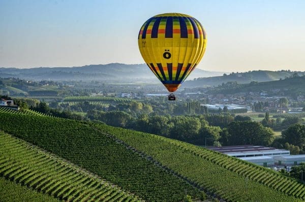 Una mongolfiera gialla vola sui vigneti delle Langhe